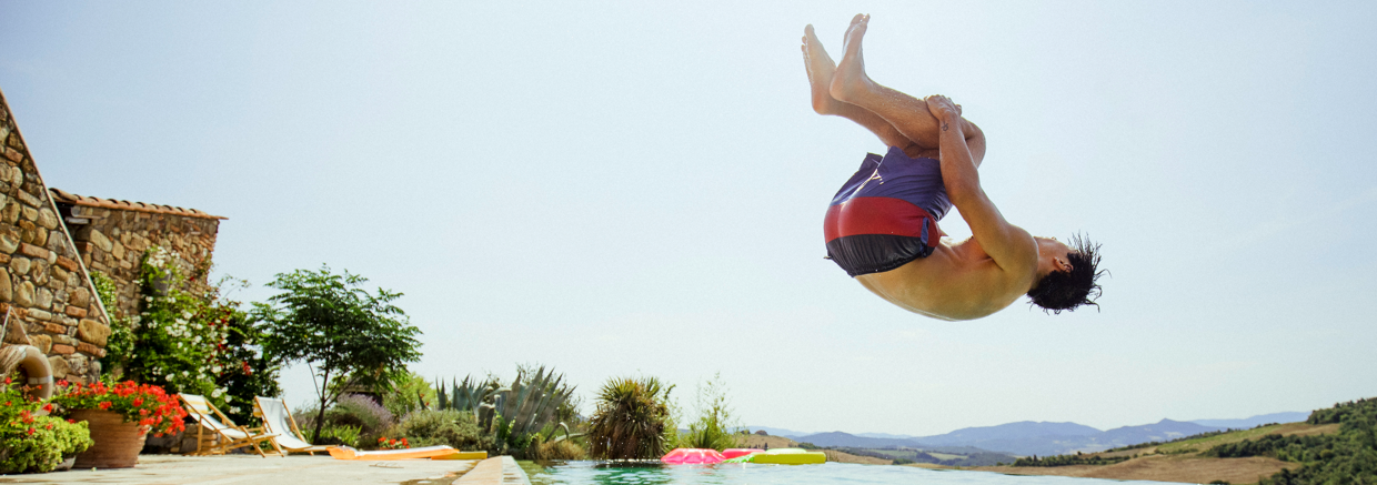 Man doing a backflip nearby a pool